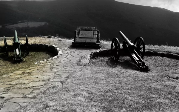4K Ultra HD desktop wallpaper featuring historical military artillery positioned on a stone-paved hill with dramatic mountainous landscape in the background.