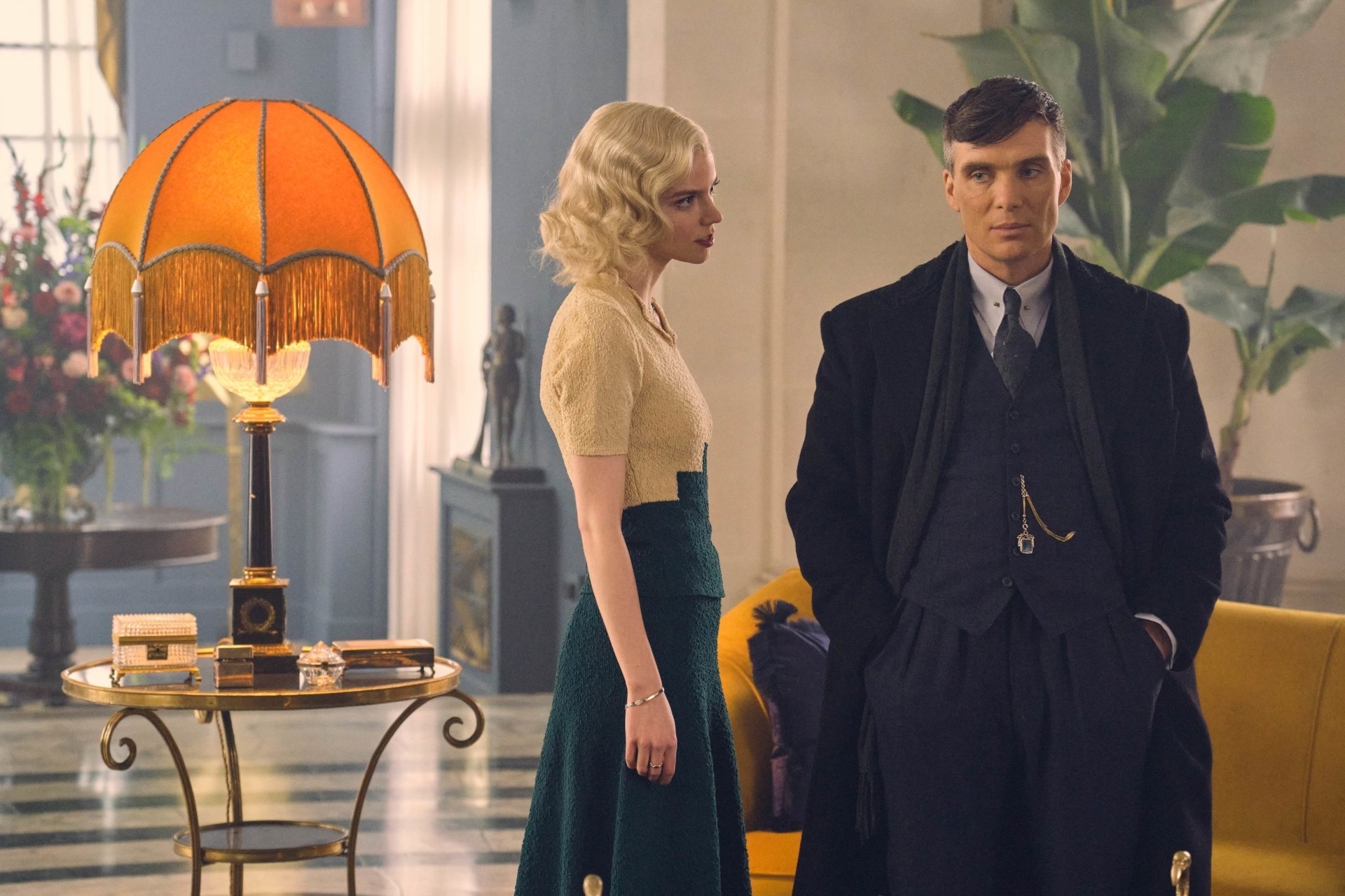 HD desktop wallpaper from TV show Peaky Blinders: Thomas Shelby and a blonde companion portrayed by actors stand in a stylish 1930s lounge, moody vintage lighting.