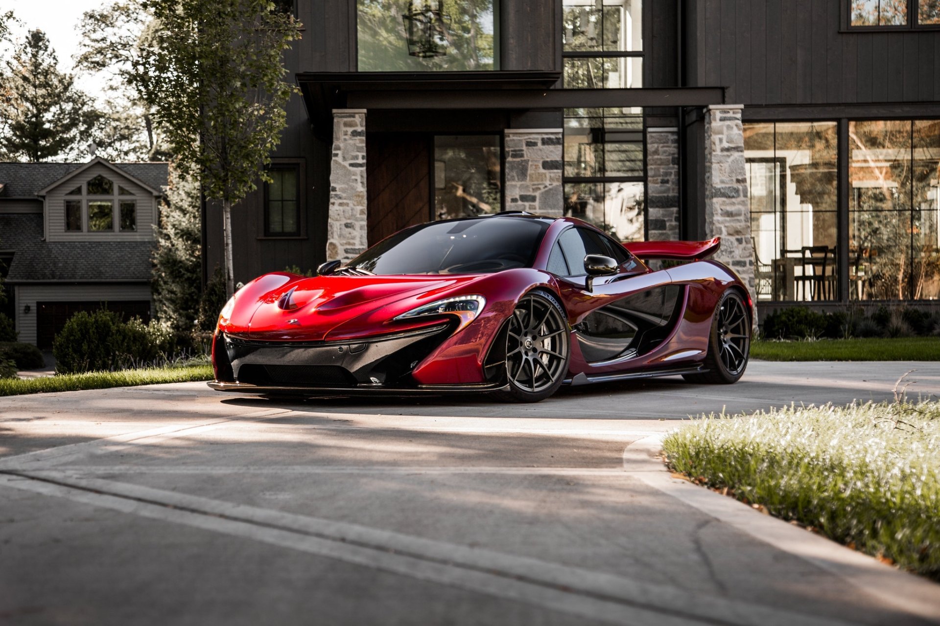 HD PC desktop wallpaper featuring a red McLaren P1 parked in front of a modern house, showcasing the sleek design and dynamic curves of this high-performance vehicle.