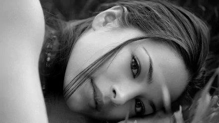 Black and white HD desktop wallpaper featuring a close-up portrait of celebrity Kristin Kreuk lying down with a calm, contemplative expression.