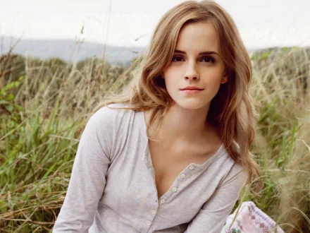 A high-definition desktop wallpaper featuring celebrity Emma Watson, set against a natural outdoor background with greenery and a clear sky.