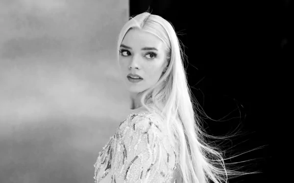 Black and white HD desktop wallpaper featuring celebrity Anya Taylor-Joy with long hair, looking over her shoulder against a blurred background.
