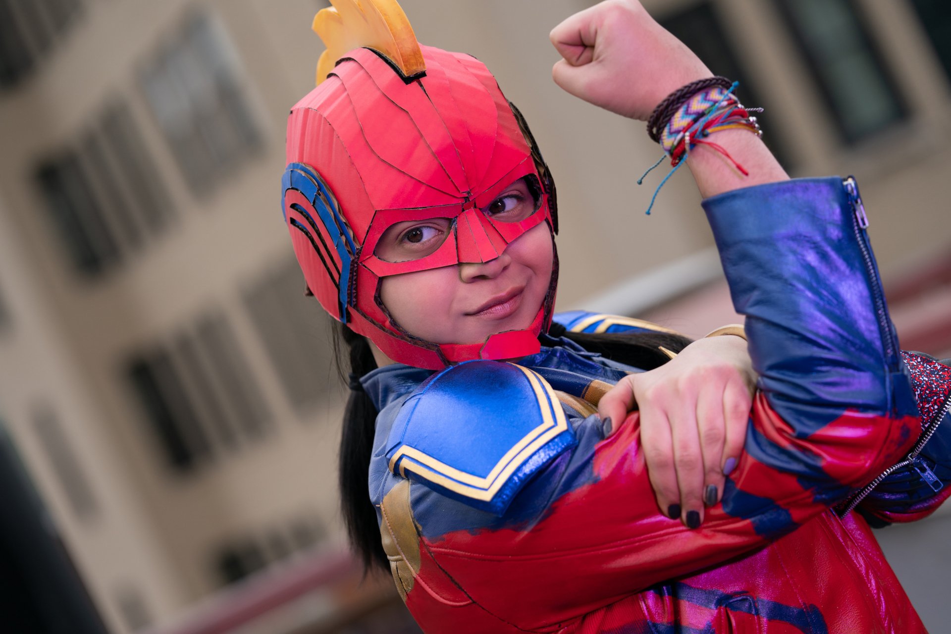 HD desktop wallpaper of Kamala Khan (Ms. Marvel) in red-and-blue costume, young superhero striking a confident flexed-arm pose with colorful bracelets from the TV show.