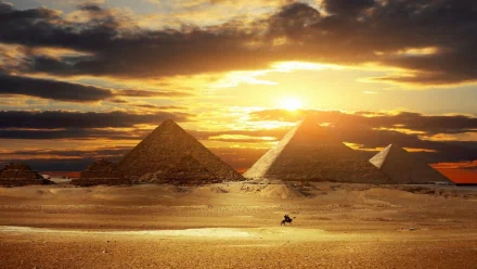 HD desktop wallpaper featuring man-made pyramids illuminated by a dramatic sunset over a vast desert landscape.