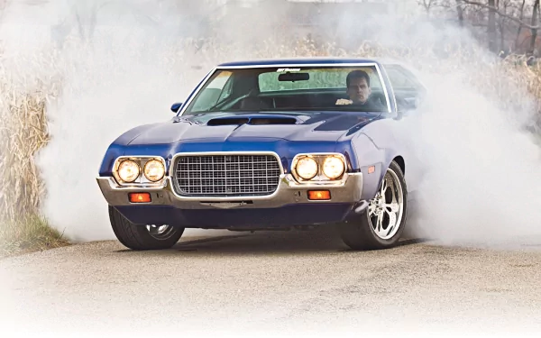 HD desktop wallpaper featuring a Ford Gran Torino Sport in motion, surrounded by tire smoke on a rural road.