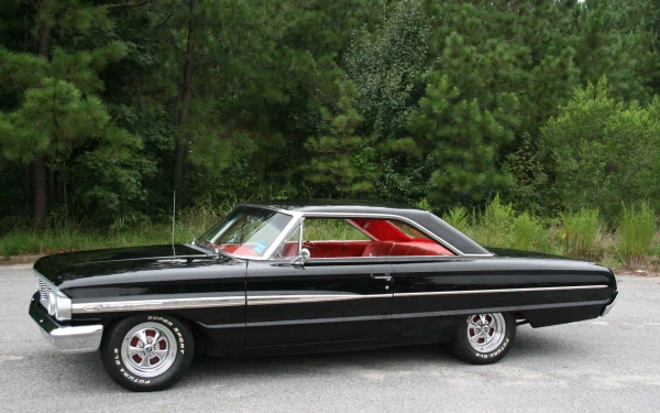 HD PC desktop wallpaper featuring a classic black Ford Galaxie 500 parked on a road with a lush green forest background.