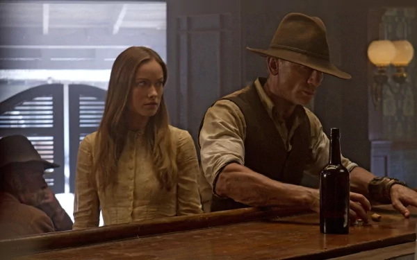 HD PC desktop wallpaper from the movie Cowboys & Aliens: a cowboy in a hat and a long-haired woman sit at a dim saloon bar, a bottle on the counter and shutters in the background.