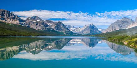 4K Ultra HD desktop wallpaper of a serene lake in the USA, showcasing clear water reflecting surrounding mountains and a vibrant blue sky with scattered clouds.