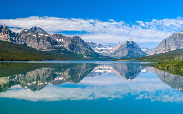 4K Ultra HD desktop wallpaper of a serene lake in the USA, showcasing clear water reflecting surrounding mountains and a vibrant blue sky with scattered clouds.