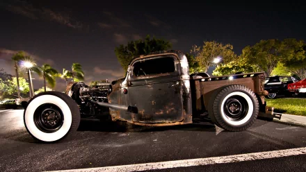 A striking rat rod vehicle parked under night skies, showcasing its vintage design and unique character. This HD wallpaper captures the essence of automotive artistry.