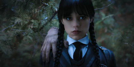 Jenna Ortega as Wednesday Addams in a dark, atmospheric scene from the TV show Wednesday, featuring her signature braids and a haunting backdrop of nature. HD desktop wallpaper.