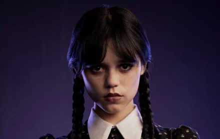HD desktop wallpaper featuring Jenna Ortega as Wednesday Addams from the TV show Wednesday, showcasing her iconic braided hairstyle and intense expression.
