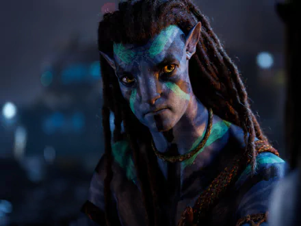 HD PC desktop wallpaper of a character from the movie Avatar: The Way of Water, featuring a detailed close-up of a blue-skinned Na'vi with cryptic markings in a dark setting.