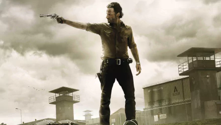 HD desktop wallpaper featuring a character from The Walking Dead TV show aiming a revolver, set against a cloudy sky and prison watchtowers in the background.