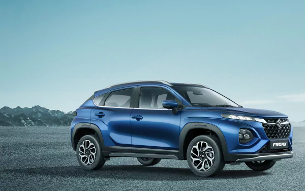 Blue Maruti Suzuki Fronx compact SUV parked on textured ground against distant mountains — 5K Ultra HD PC desktop wallpaper and background.