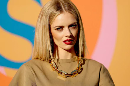 HD PC desktop wallpaper featuring celebrity Samara Weaving with blonde hair, wearing a chunky gold chain necklace and a beige top against a colorful background.