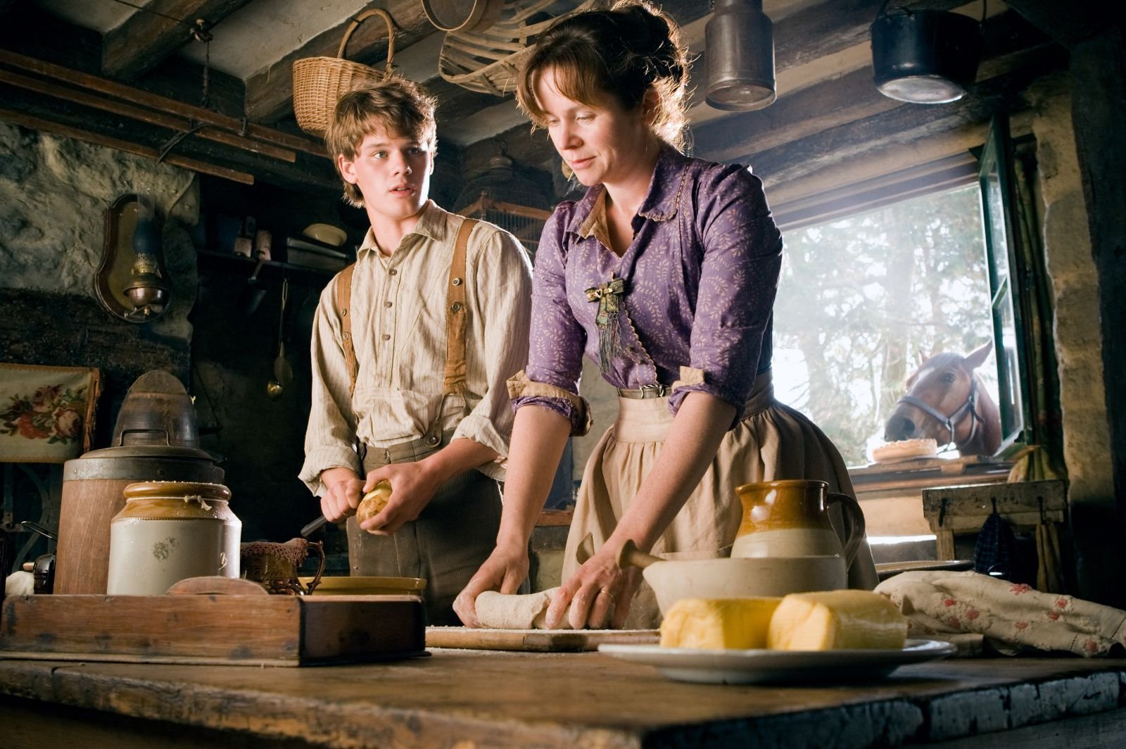 HD desktop wallpaper from the movie War Horse, showing two characters in period clothing preparing food inside a rustic kitchen.