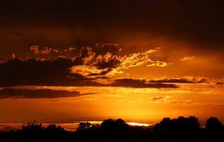 A stunning sunset over Kentucky, showcasing vibrant orange and yellow hues against dramatic clouds, captured in this 4K Ultra HD desktop wallpaper.
