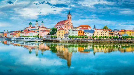 Passau cityscape along the Danube River with colorful buildings and church spires reflected in calm water, captured in vibrant 4K Ultra HD resolution.