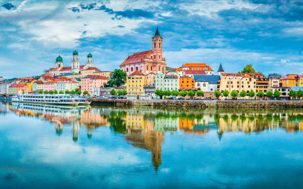 Passau cityscape along the Danube River with colorful buildings and church spires reflected in calm water, captured in vibrant 4K Ultra HD resolution.