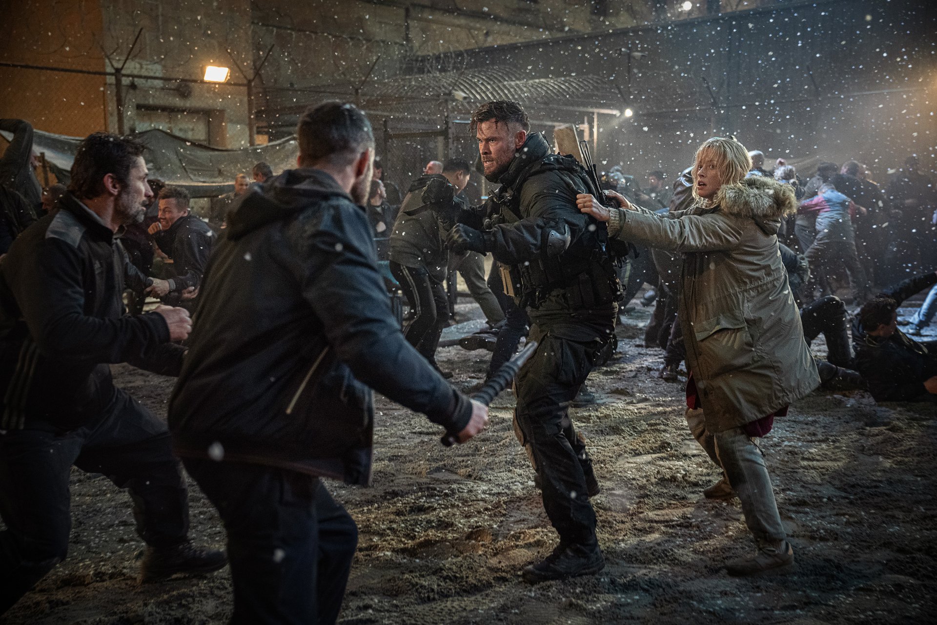 Action-packed scene from the movie Extraction 2 featuring Chris Hemsworth and Tinatin Dalakishvili amidst chaos and snowfall, set as a high-definition desktop wallpaper.