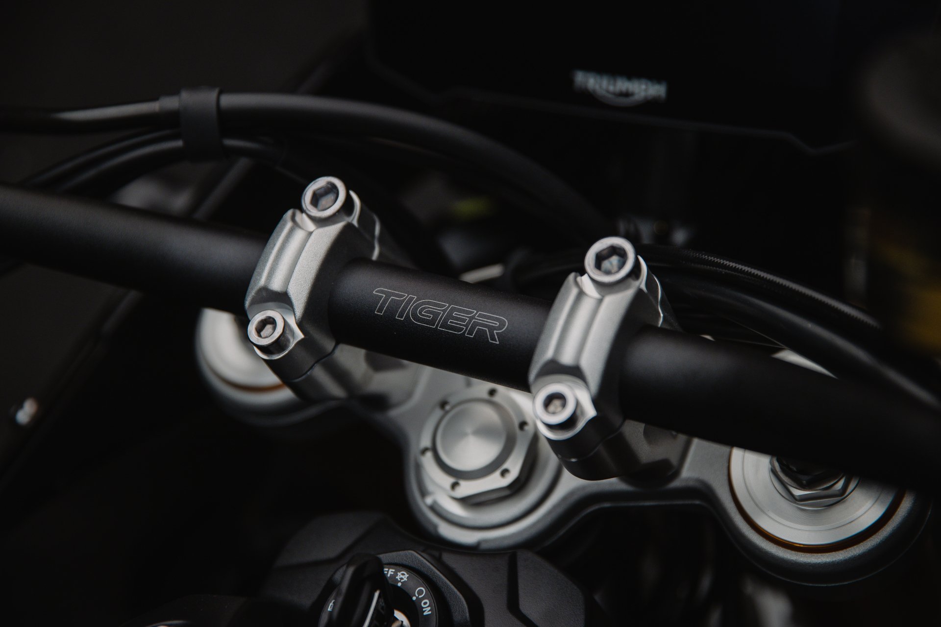 HD desktop wallpaper featuring a close-up detail of the Triumph Tiger 900 Rally Aragón motorcycle's handlebar and branding.