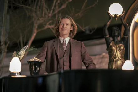 HD wallpaper of Sam Reid from 'Interview with the Vampire', standing elegantly with vintage lamp posts in the background.