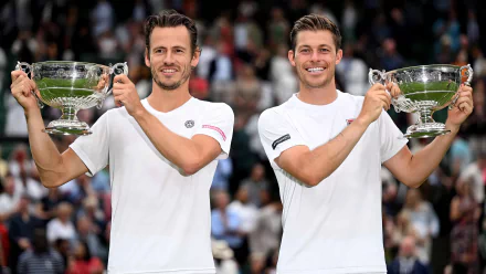 Neal Skupski and Wesley Koolhof celebrate their victory at Wimbledon 2023, holding their trophies aloft amidst an enthusiastic crowd, capturing the essence of tennis success.