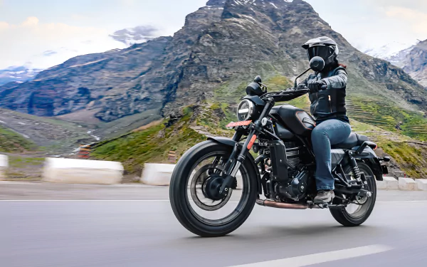 A rider on a Harley-Davidson X440 maneuvers along a scenic mountain road, showcasing the sleek design of this iconic motorcycle against a breathtaking backdrop.