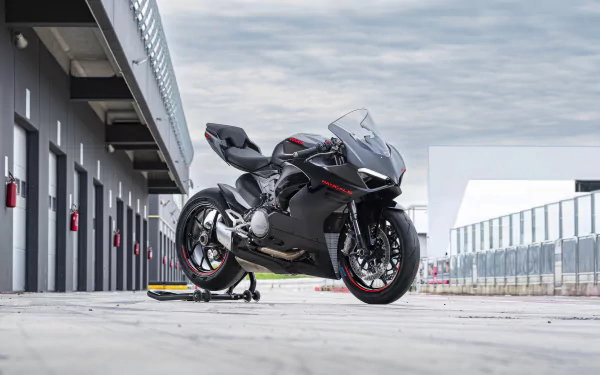 HD desktop wallpaper featuring a Ducati Panigale V2 motorcycle parked at a racing pit lane with overcast skies in the background.