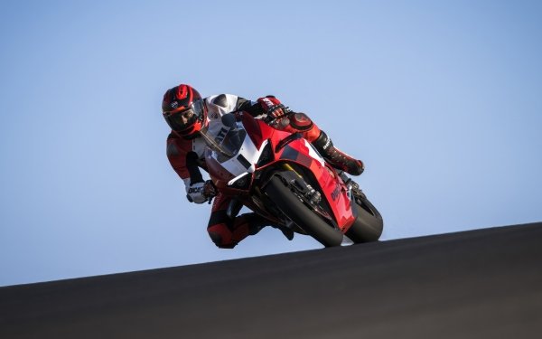 A rider on a Ducati Panigale V4 R motorcycle racing on a track, set against a clear sky, perfect for HD desktop wallpaper and background.