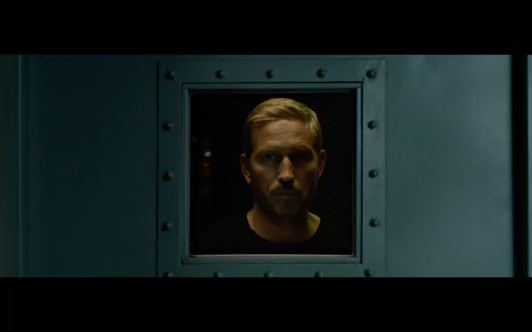 HD desktop wallpaper featuring a serious man looking through a ship's porthole, associated with the movie Sound of Freedom, evoking a mood of anticipation and solemnity.