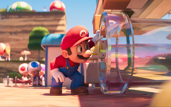 HD desktop wallpaper from the 2023 movie Super Mario Bros. featuring Mario interacting with a clear, cylindrical device in a vibrant Mushroom Kingdom setting.