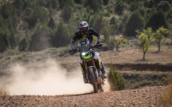 A rider maneuvers a Triumph Tiger 900 Rally Pro through a dusty, off-road landscape, showcasing the vehicle's rugged capability in a stunning HD wallpaper.
