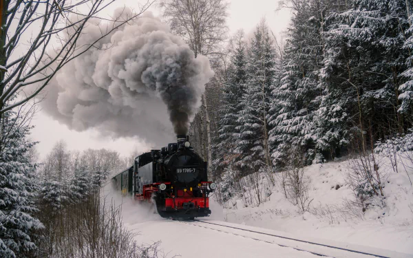 HD desktop wallpaper featuring a steam train chugging through a snowy forest landscape, with thick smoke billowing from its chimney.