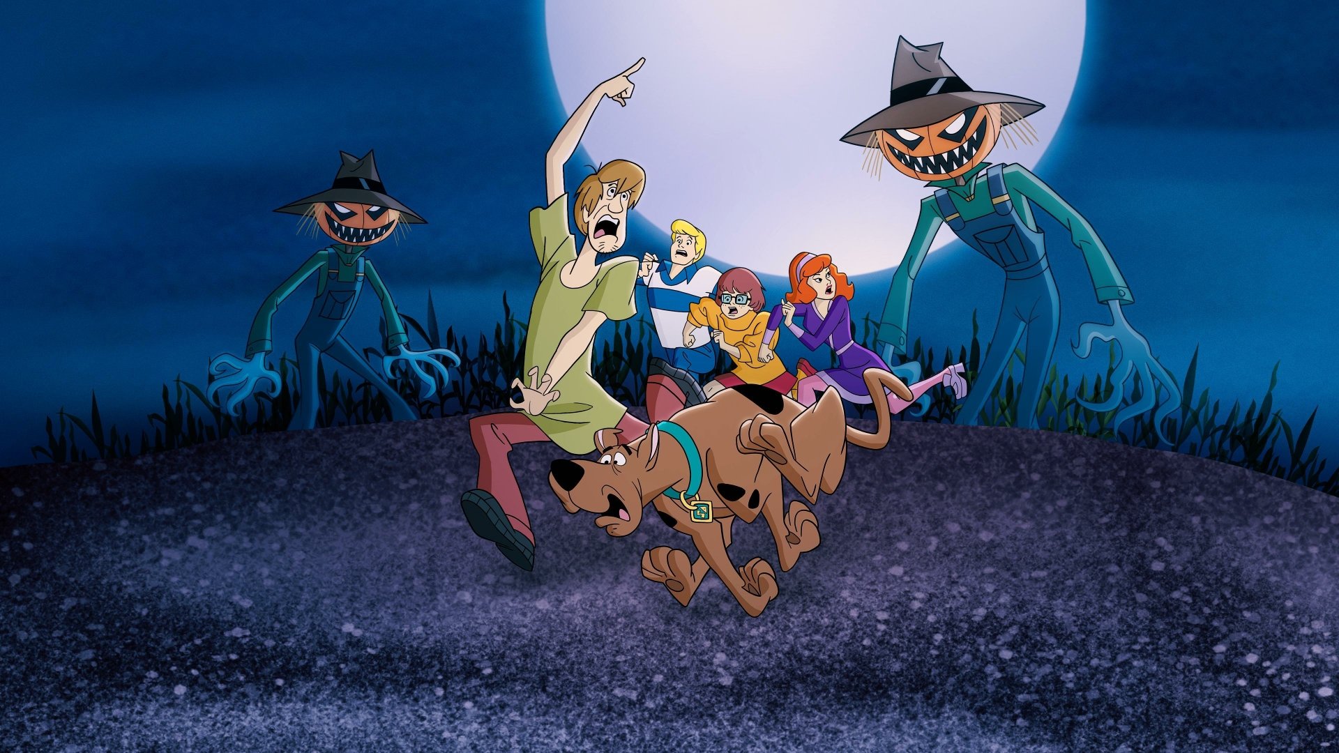 Scene from the TV show What's New, Scooby-Doo? featuring Scooby, Shaggy, Velma, Daphne, and Fred running from pumpkin-headed scarecrows in a 4K Ultra HD PC wallpaper.