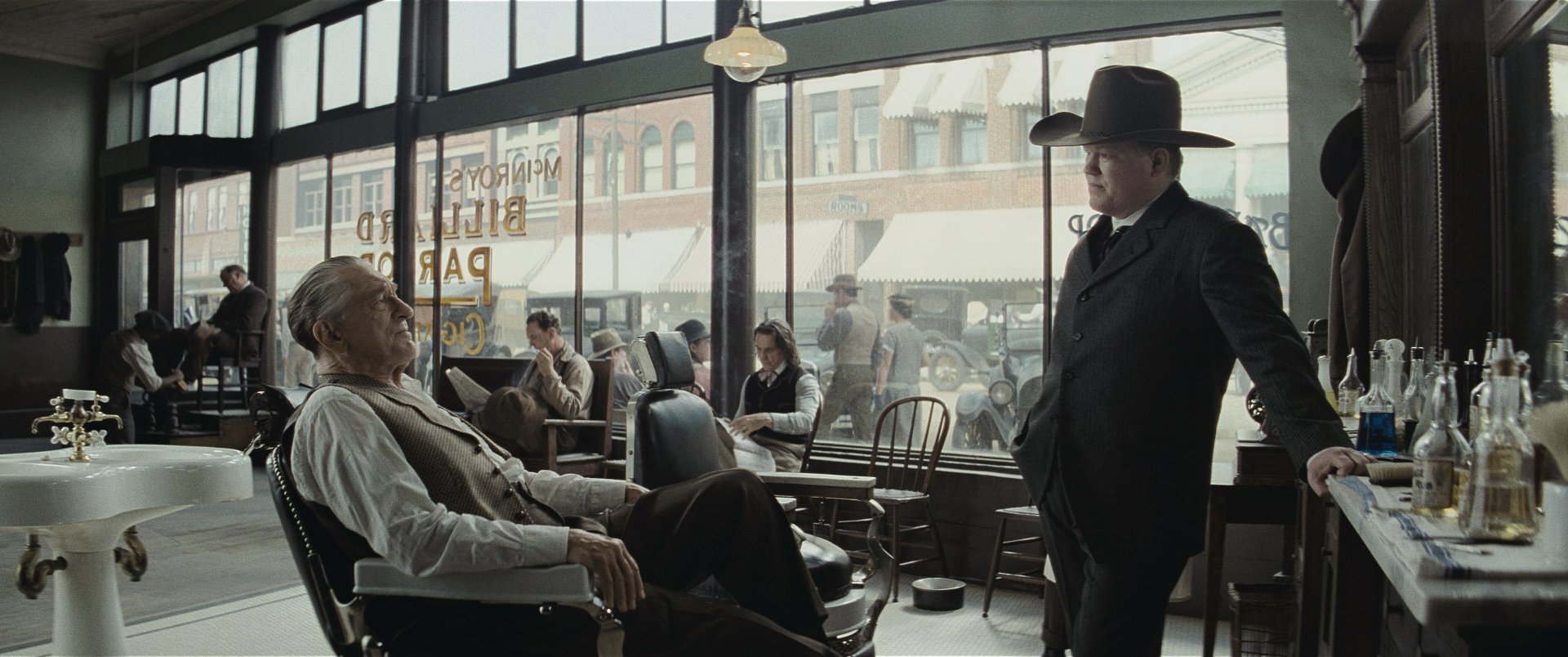 HD wallpaper featuring a still from 'Killers of the Flower Moon' with two characters in a vintage barbershop setting, encapsulating the film's period atmosphere.
