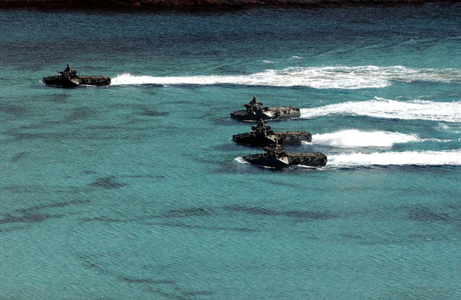 A striking HD wallpaper featuring military amphibious vehicles navigating through clear blue waters, showcasing their agility and power in a dynamic scene.