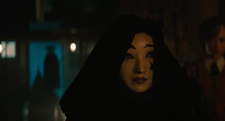A haunting scene from the movie A Haunting in Venice, featuring a mysterious figure in a hooded cloak and mask, set against a dimly lit backdrop. HD desktop wallpaper.