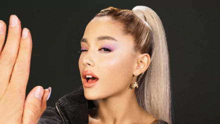 High-definition desktop wallpaper featuring a female celebrity with a high ponytail, dramatic purple eyeshadow, and a black outfit against a dark background.