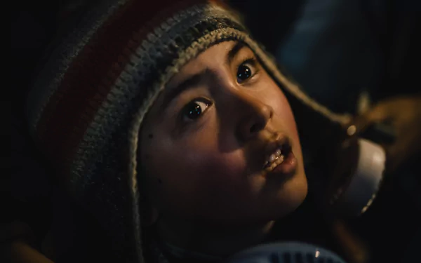 A young character gazes upwards with intrigue, wearing a knitted hat, in this HD desktop wallpaper from the movie *The Creator* (2023).