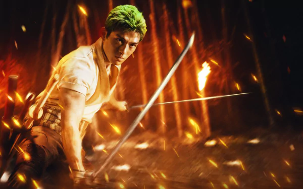 Roronoa Zoro from the One Piece live-action TV show poised with a sword amid fiery embers, featured in a dynamic HD PC desktop wallpaper background.