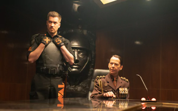 A scene from the TV show Loki features two characters in a dimly lit room, one in tactical gear and the other in a military uniform, set against a striking backdrop.