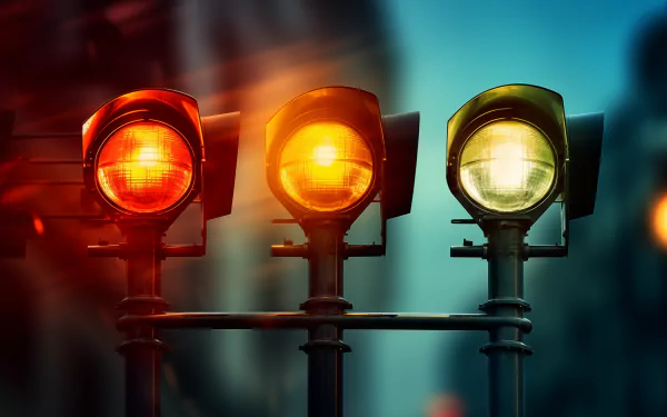 High-definition desktop wallpaper featuring a trio of traffic lights glowing red, amber, and green against a blurred city background.