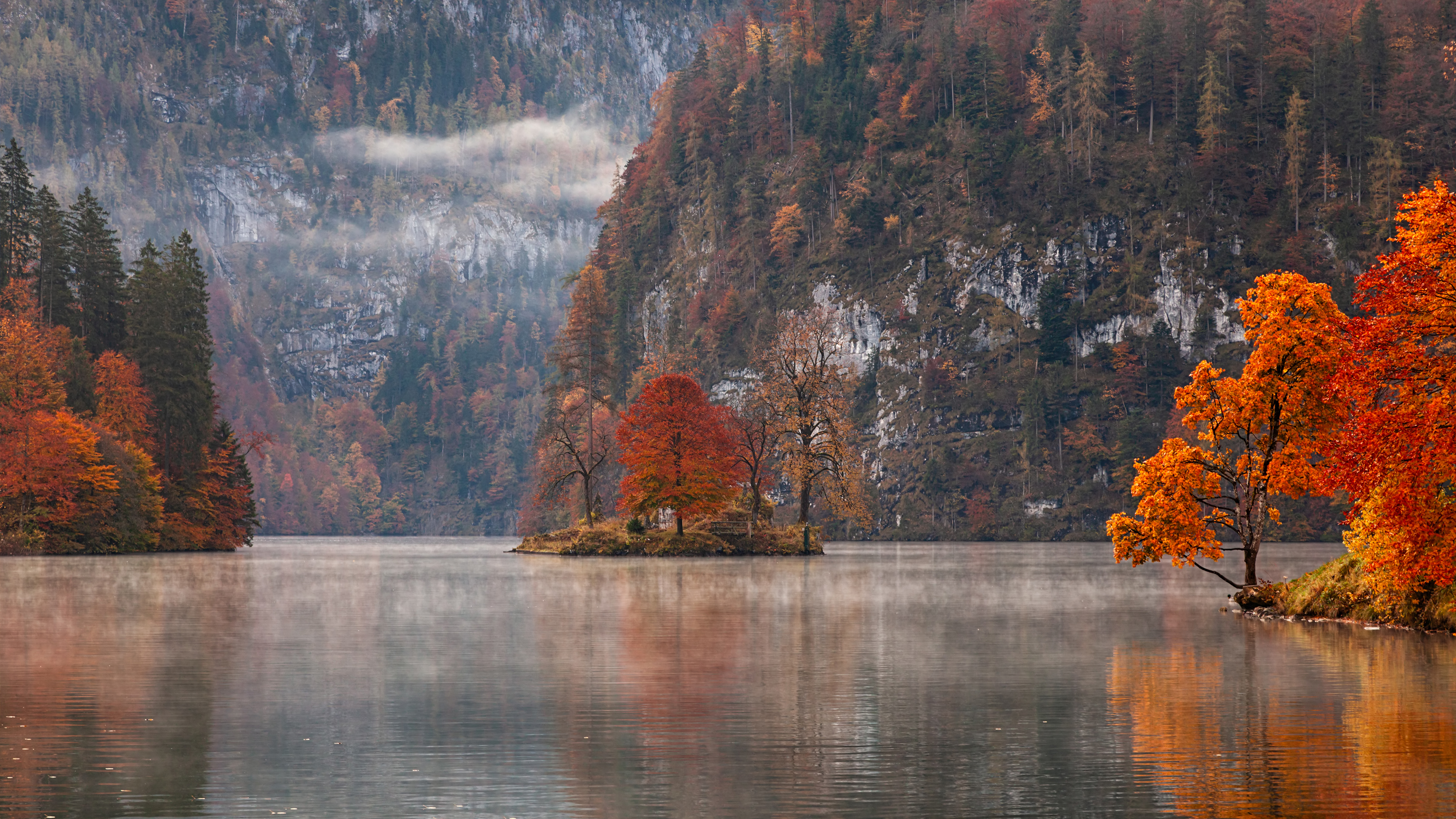 Autumn scenery HD desktop wallpaper featuring a serene lake with vibrant orange trees and a misty mountain backdrop.