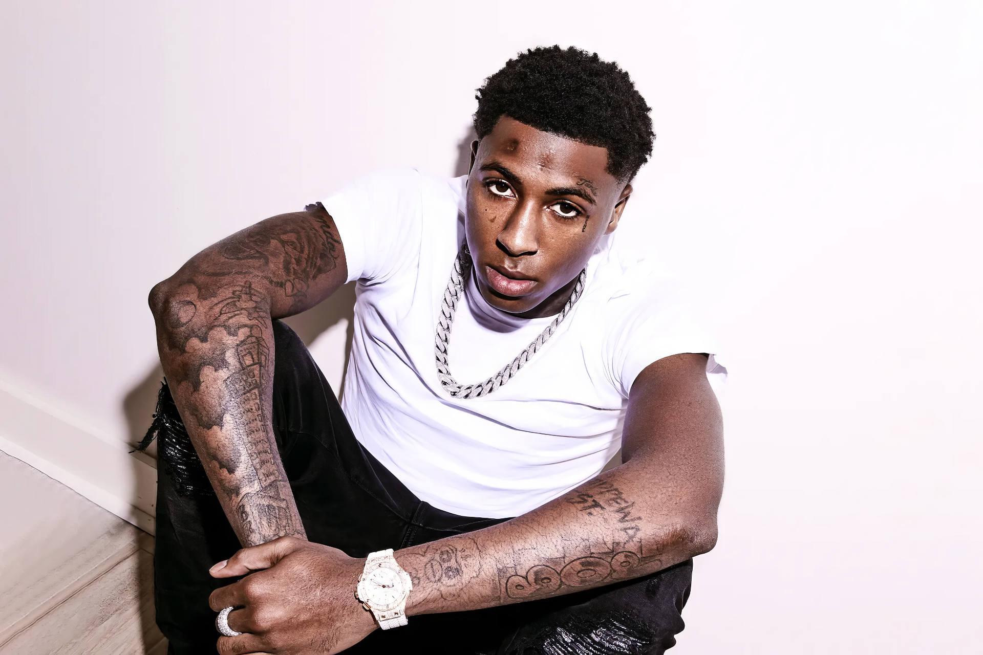 Alt Text: HD wallpaper of a young male artist with tattoos sitting down, representing YoungBoy Never Broke Again, with a music theme for desktop backgrounds.