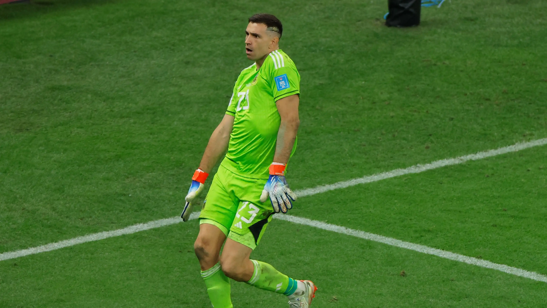 Emiliano Martinez, goalkeeper for the Argentina National Football Team, celebrates on the field in vibrant green kit. A striking HD wallpaper for soccer fans.