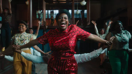 HD wallpaper featuring a joyful scene from The Color Purple 2023 movie with a woman smiling and dancing brightly dressed in red.
