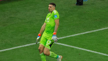 Emiliano Martinez, goalkeeper for the Argentina National Football Team, celebrates on the field in vibrant green kit. A striking HD wallpaper for soccer fans.