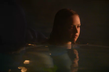 HD wallpaper of a serene night swim scene from a movie, featuring a person submerged in water with a contemplative expression.